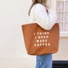 Large tan tote bag with white text saying 