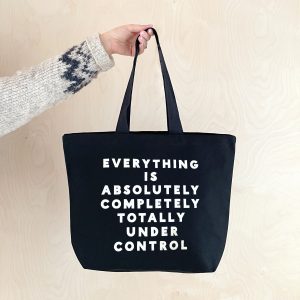 Bold black tote bag with white text reading "Everything is absolutely completely totally under control," perfect for stylish shopping and casual outings, showcasing trendy and functional accessories.