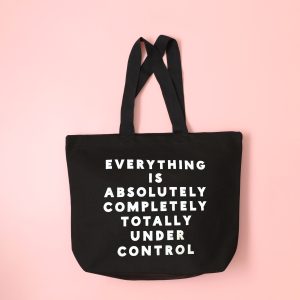 Black tote bag with white printed quote "Everything is absolutely completely totally under control" on pink background, ideal for casual outings and expressing fun, confident style.