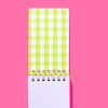 Pink and green checkered spiral notepad on bright pink background, ideal for food and catering branding, showcasing vibrant freshness, and perfect for customizing menus or food packaging visuals.
