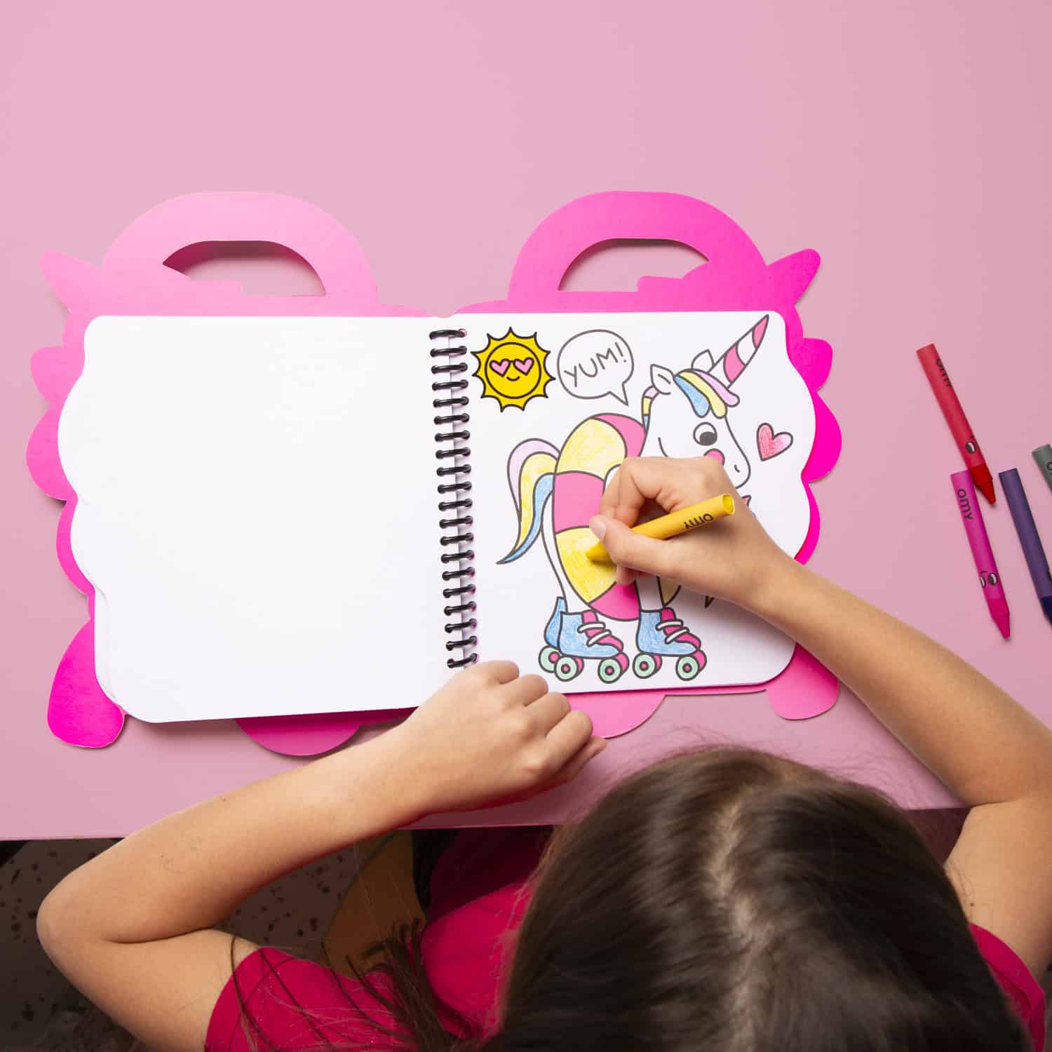 Colorful unicorn roller skate coloring book on a pink unicorn-themed table, child coloring with markers, fun and creative activity, perfect for kids' entertainment and art.