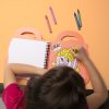 Colorful crayon markers on an illustration activity book, kid's creative arts and crafts at The Wraperie, showcasing fun and artistic snack-themed coloring pages.
