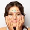 Colorful confetti stickers on a smiling woman's face, emphasizing playful body art and face decoration ideas for parties and celebrations.