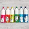 Brightly colored bottles with playful doodle labels and inspiring messages, perfect for creative activities and celebrations at The Wraperie.