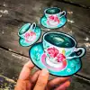 Colorful coffee cup magnet with floral design, perfect for kitchen decor, on rustic wooden surface.