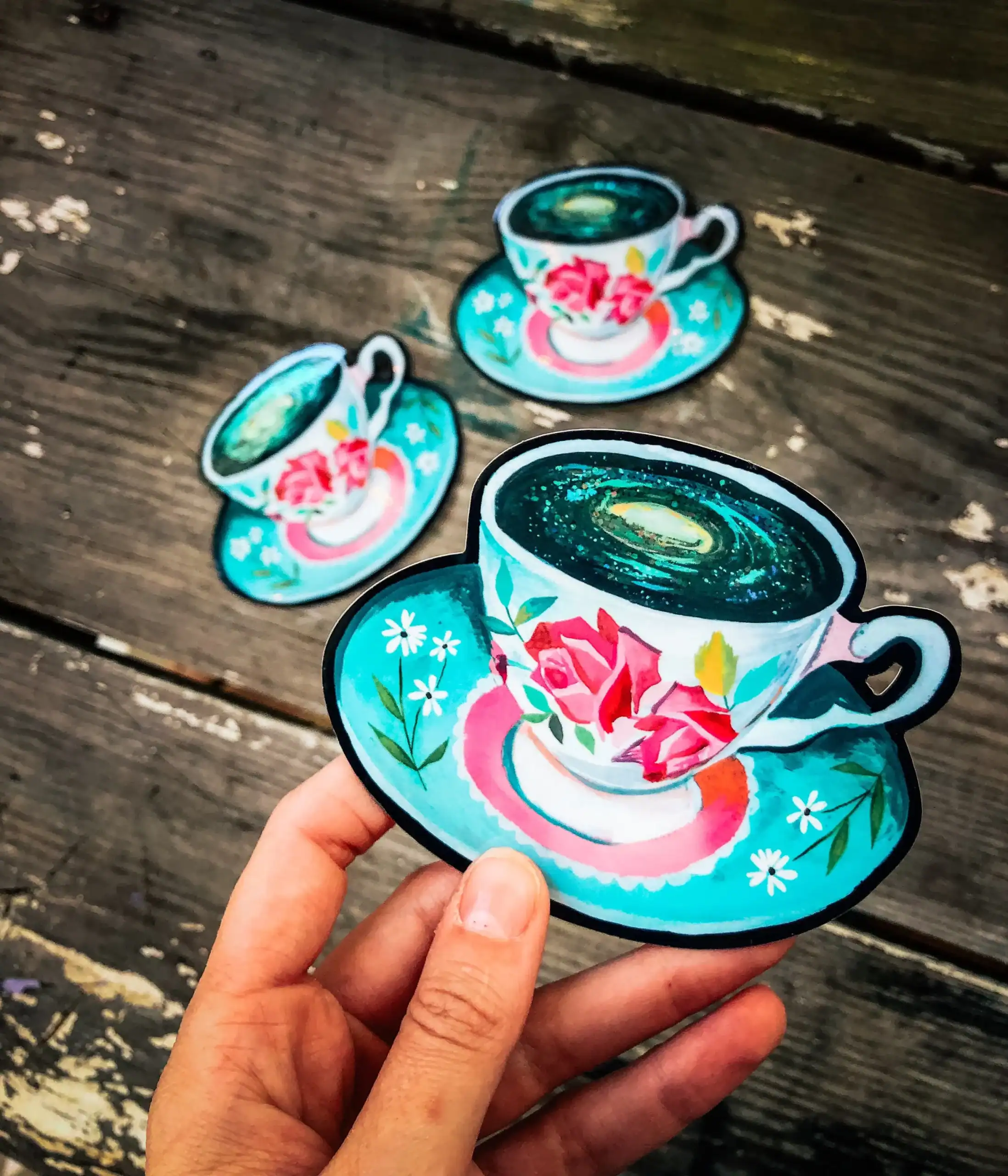 Colorful coffee cup magnet with floral design, perfect for kitchen decor, on rustic wooden surface.