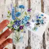 Colorful floral sticker featuring blue, purple, and pink flowers in a glass jar design, perfect for decorating laptops, water bottles, or notebooks. Bright and vibrant botanical artwork.