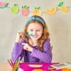 Colorful fruit-themed craft activity for kids at The Wraperie, featuring a young girl drawing and decorating paper fruit cutouts, promoting creativity and healthy eating awareness.