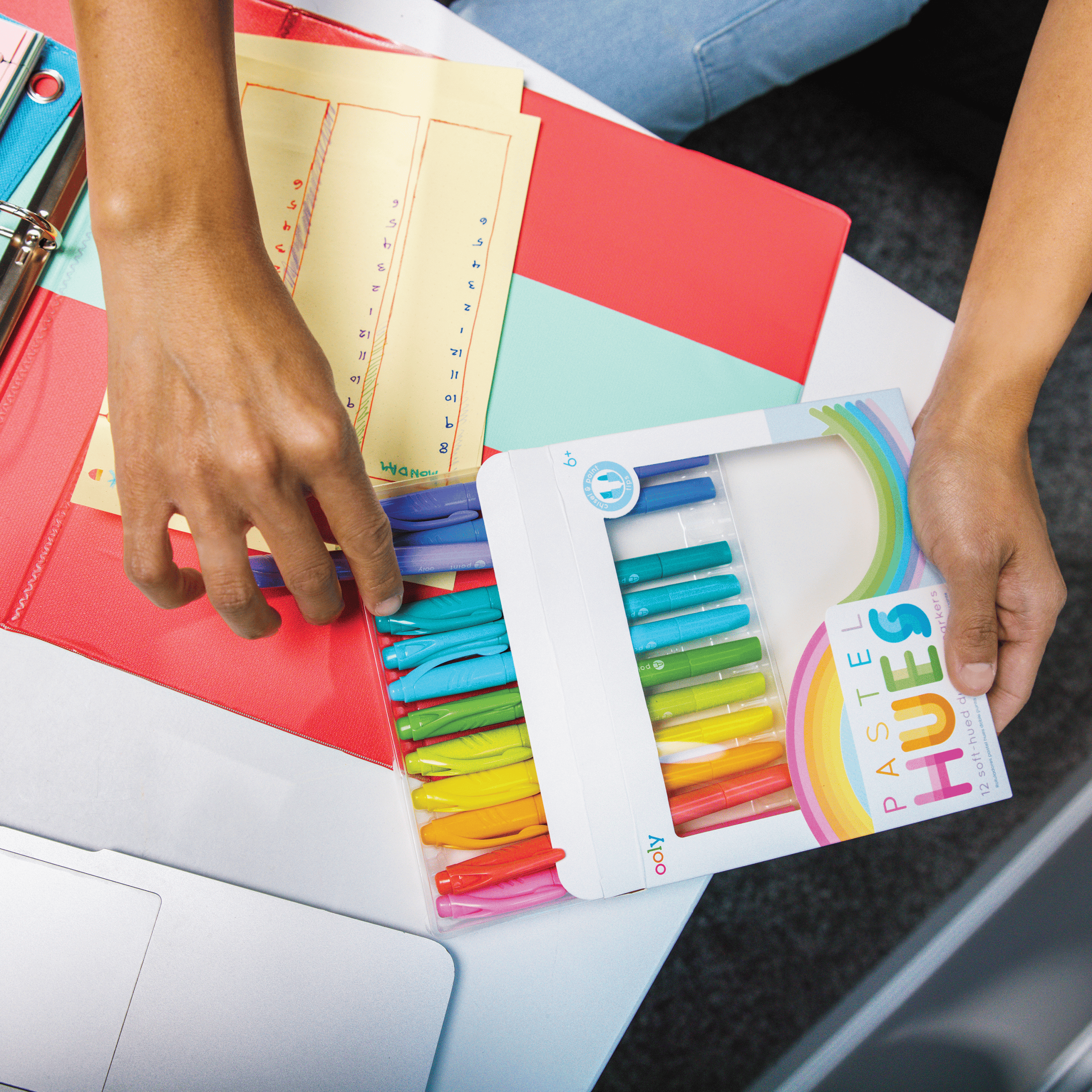 Colorful highlighters and notebooks on a desk at The Wraperie, a creative workspace, showcasing organization and office supplies ideal for personal or professional use.
